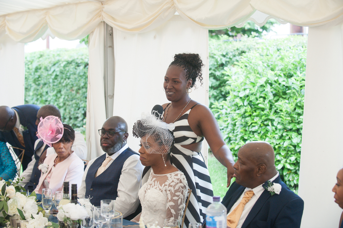 Wedding guests and the top table inside a marquee on a warm summer day