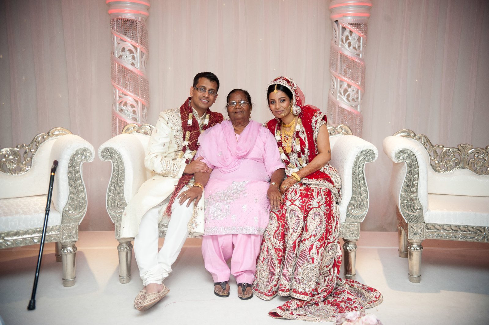 The bride on the reception stage with her grandmother in a pink sari at an Asian wedding