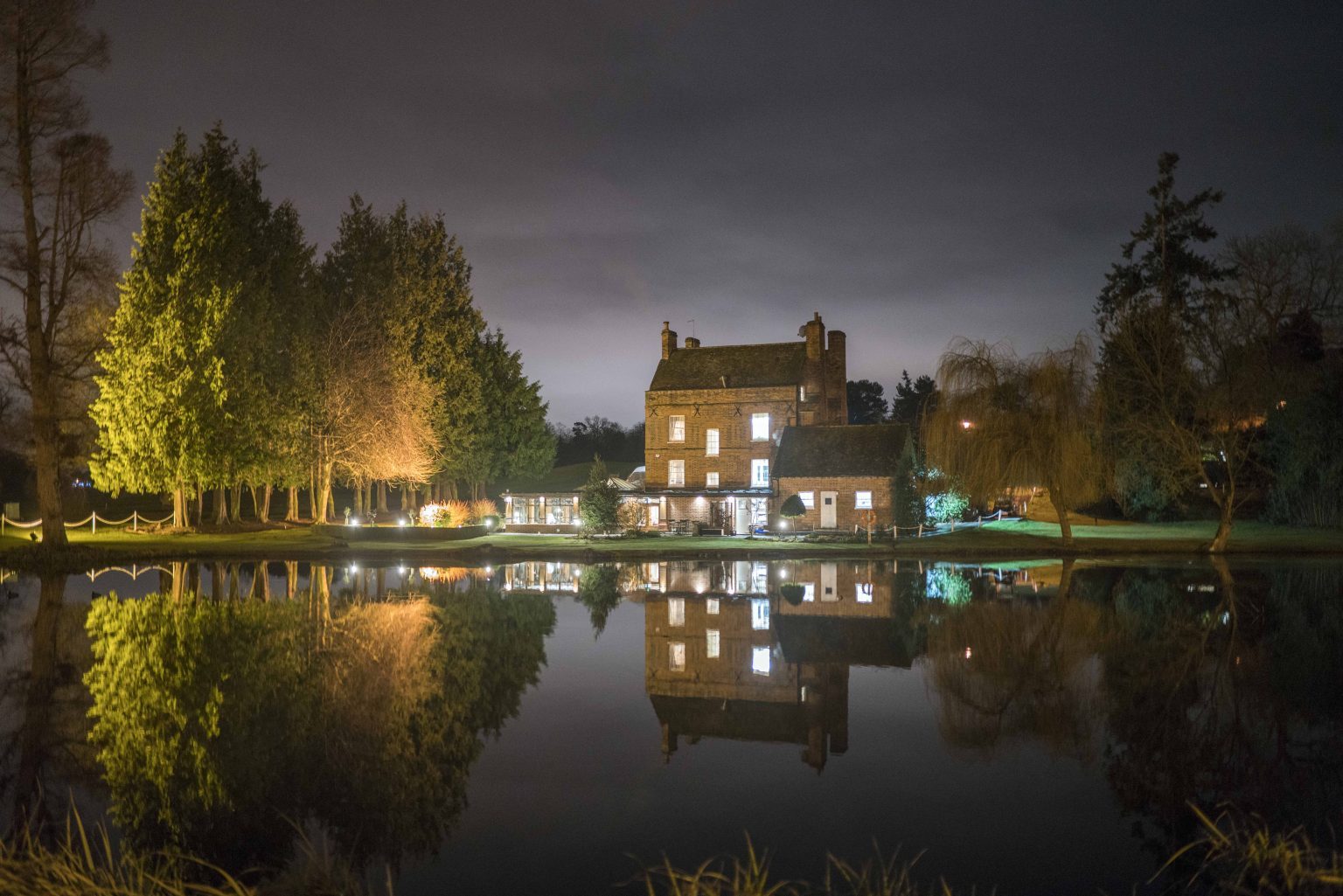 Brocket Hall in Welwyn, Hertfordshire, lit at night and reflected in the lake