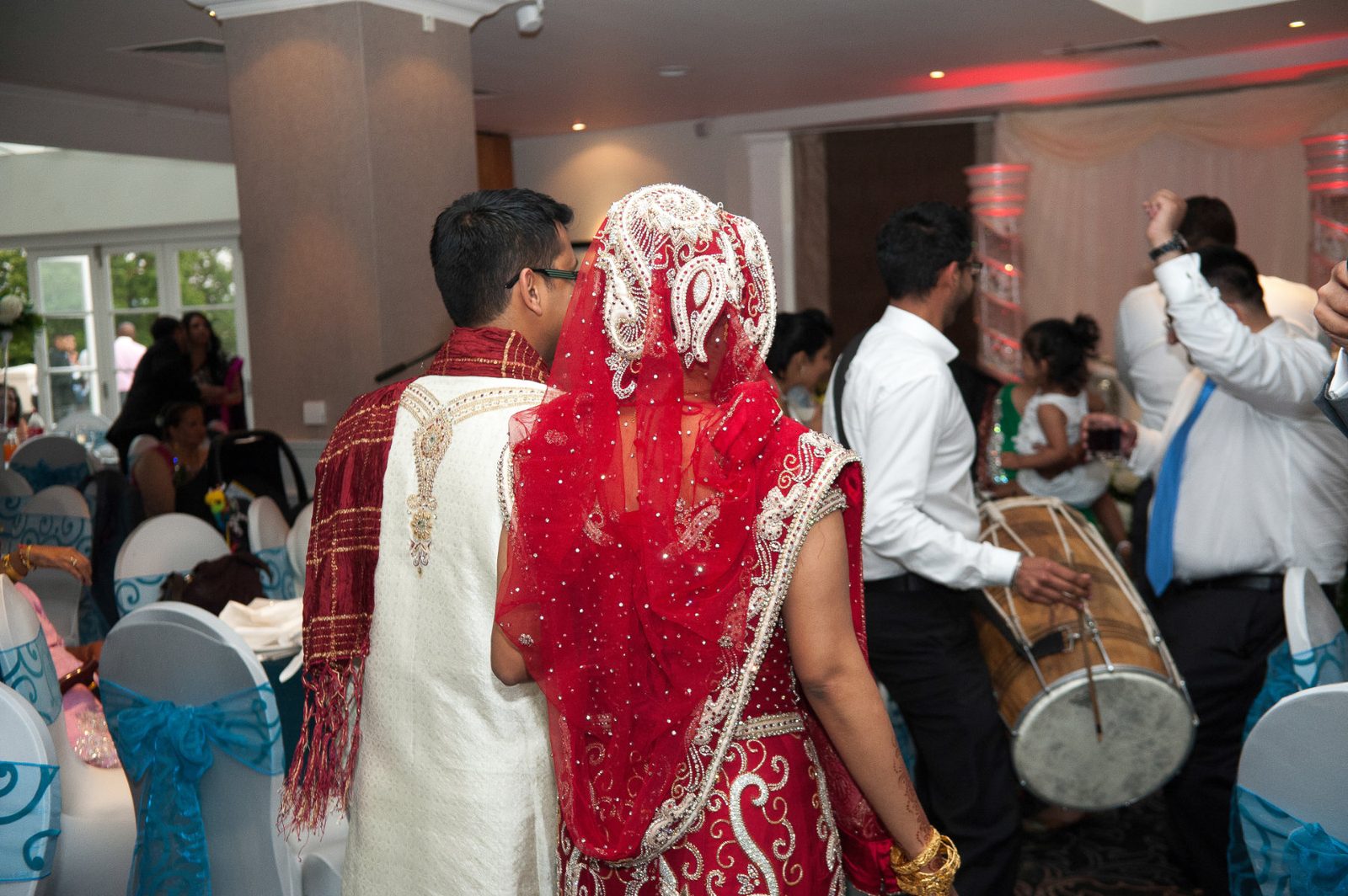 A dhol drummer greeting the couple as they arrive at the reception after an Asian wedding