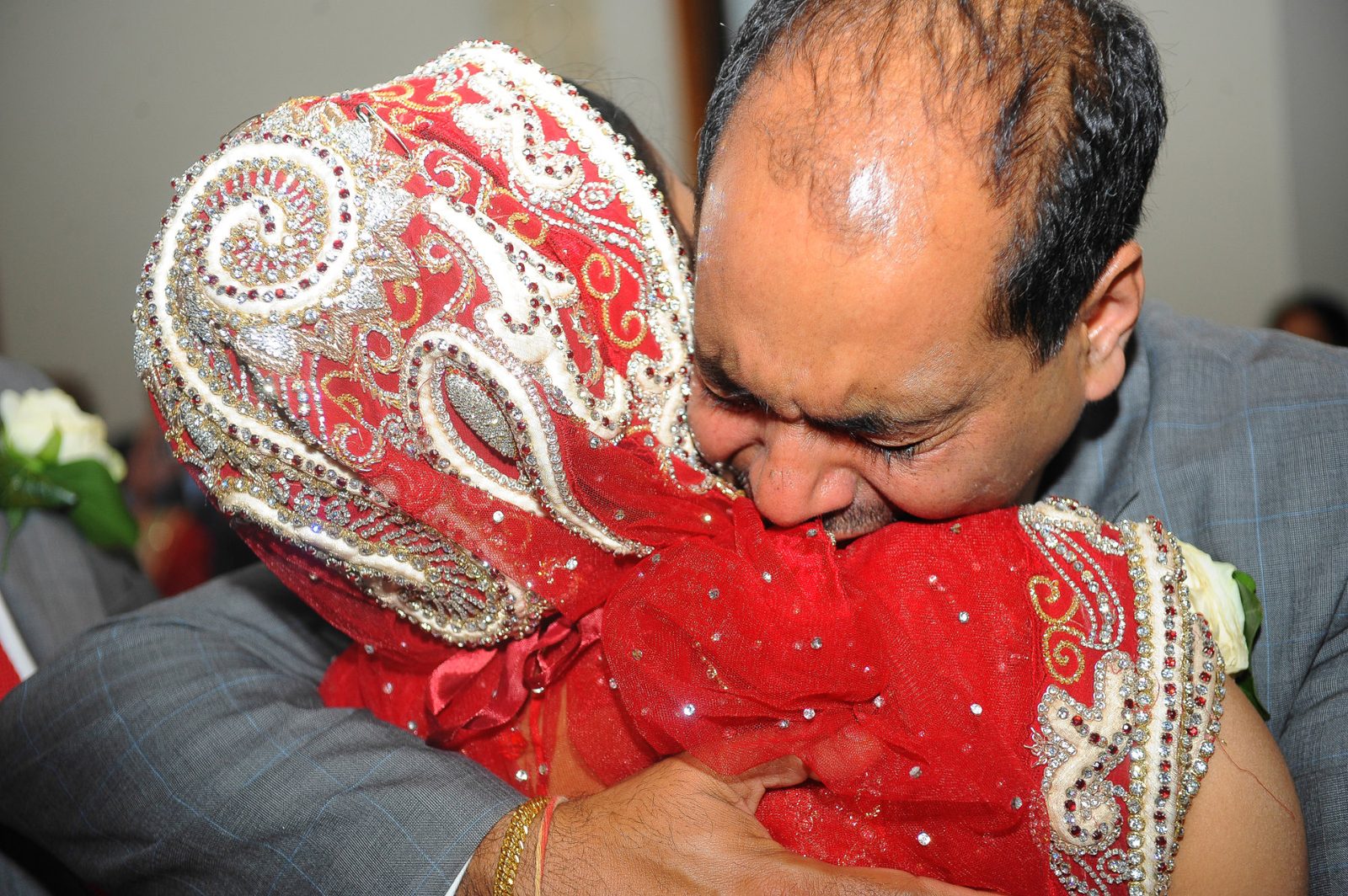 The bride held by her father at the vidaai, the leaving, at the end of an Asian wedding